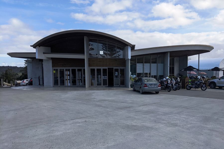 The curved roof and glass frontage of the Mangawhai Museum, seen across its car park.
