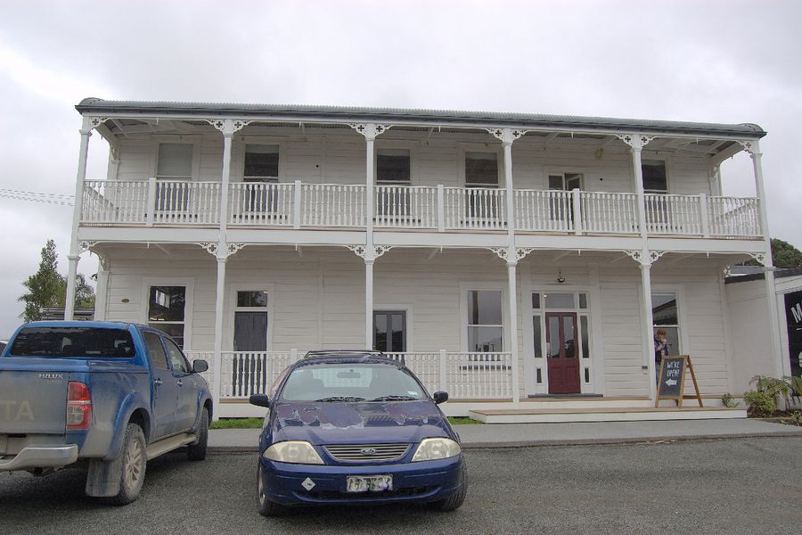 The two-storey white Mangawhai Tavern with its long verandah and balcony.